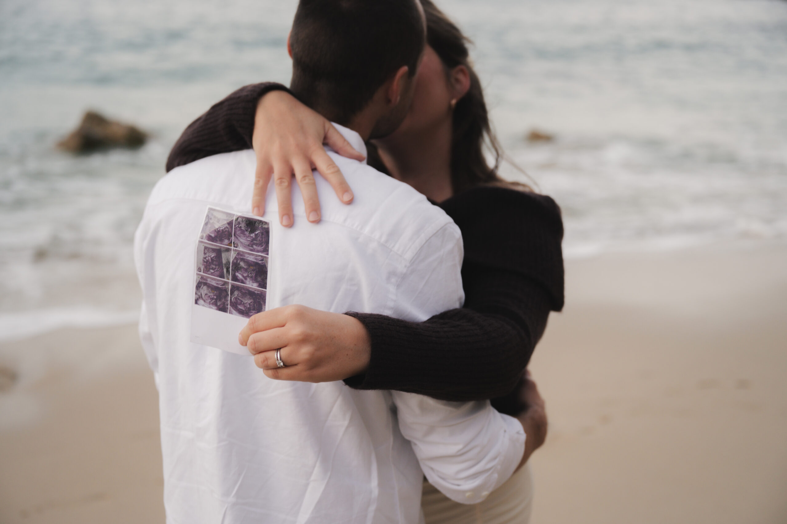 Séance photo en couple sur la plage qui attendent un enfant